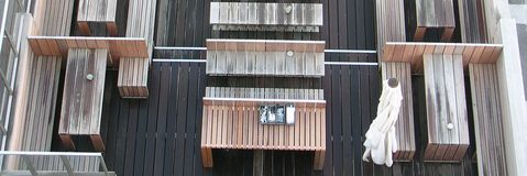 Luftaufnahme einer Holzterrasse mit Tisch, Bänken und einer zusammengefalteten weißen Markise