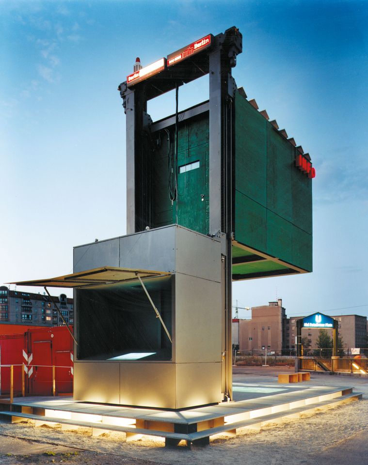 Moderner Pavillon mit großem, erhöhtem Kubus auf Metallrahmen in urbaner Umgebung bei Dämmerung