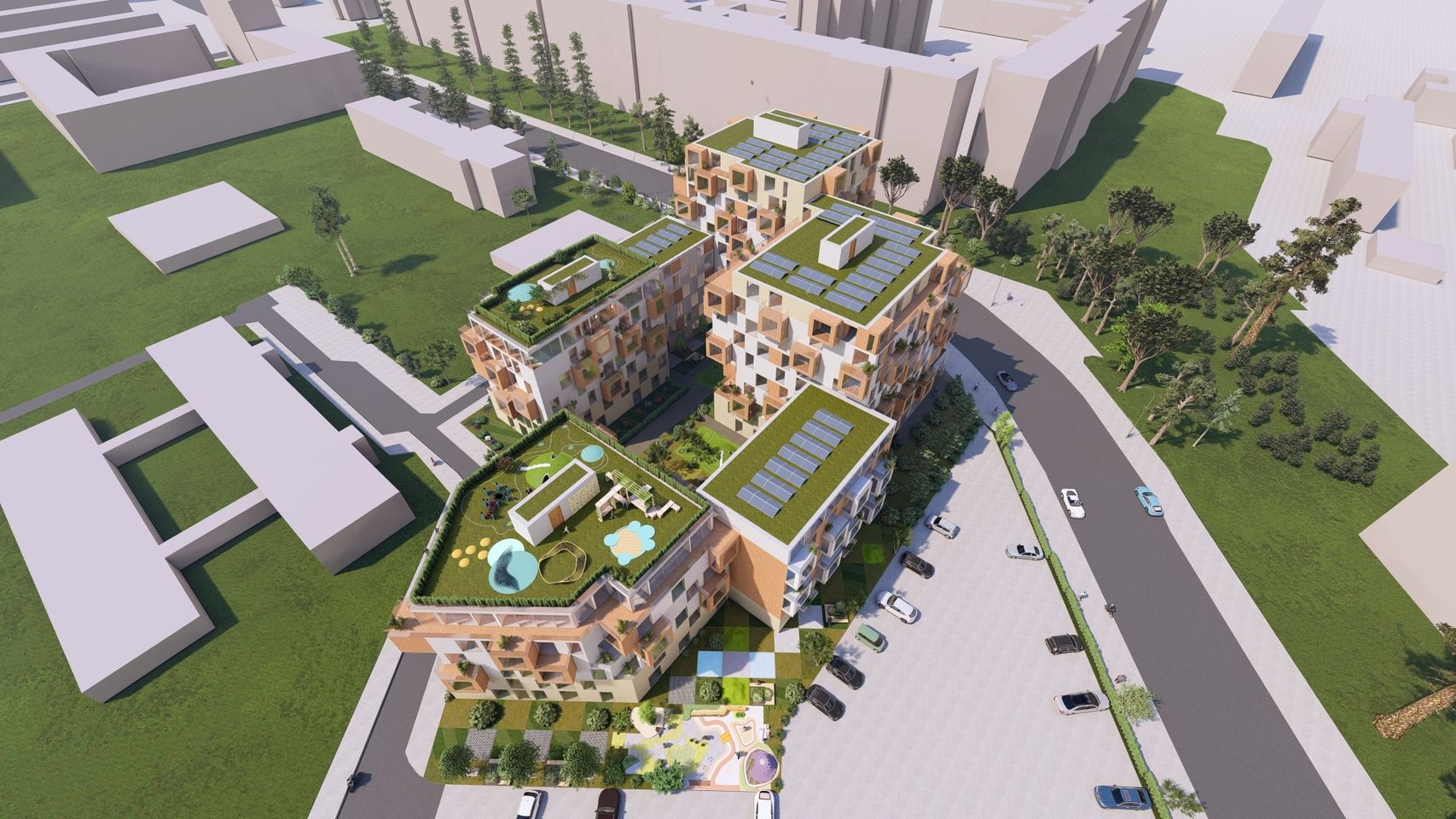 Luftaufnahme von vier modernen, kubischen Gebäuden mit begrünten Dächern und Solarpaneelen in einem städtischen Umfeld mit Parkplätzen und Bäumen